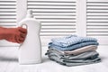 Stack of folded clothes and detergent bottle in female hand. Housework Royalty Free Stock Photo