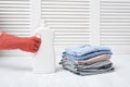 Stack of folded clothes and detergent bottle in female hand. Housework Royalty Free Stock Photo