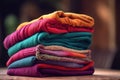 a stack of folded clothes sitting on top of a wooden table next to a bottle of water and a cup of coffee on the table