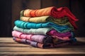 a stack of folded cloths sitting on top of a wooden table next to a wooden wall and a wooden door in the back ground Royalty Free Stock Photo