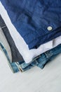 Stack of Folded Cotton Pants Shirts Jeans on White Wood Background Shelf. Eco Fashion Authentic Classic Unisex Style Natural