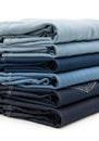 Stack of folded denim jeans in varying shades of blue, ranging from light to dark. The Royalty Free Stock Photo