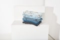 a stack of folded jeans lies on a white stepped podium close-up. online shopping Royalty Free Stock Photo