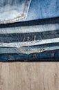 A stack of folded jeans on wooden background. Close-up of jeans in different colors. Denim background. Selective focus Royalty Free Stock Photo