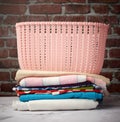 Stack of folded laundry and empty laundry basket, brown brick wall background Royalty Free Stock Photo