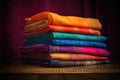 a stack of folded silk sarees in vibrant hues