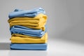 A stack of folded soft, smooth clothes. Light blue and yellow T-shirts. Things on a light background with space for text. Concept Royalty Free Stock Photo