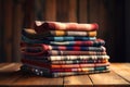 Stack of folded various colorful plaids on a wooden table. Wooden walls background