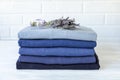 Stack of folded warm knitted men`s sweaters in blue and a bunch of dried lavender, care of clothes aroma and protection Royalty Free Stock Photo