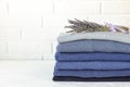 Stack of folded warm knitted men`s sweaters in blue and a bunch of dried lavender, care of clothes aroma and protection Royalty Free Stock Photo