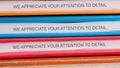 A stack of folders in vibrant colors displays a repeated message emphasizing the importance of attention to detail in