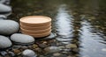A stack of four beige round coasters is positioned on a flat stone in a shallow stream. The Royalty Free Stock Photo