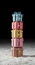 Stack of four colorful gift boxes with ribbon bows, arranged vertically on a snowy surface. Royalty Free Stock Photo