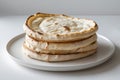 Stack of four round flatbreads with browned edges on a white plate against a white background Royalty Free Stock Photo