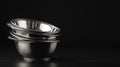 Four shiny silver bowls stacked on a sleek black surface, creating an elegant and modern kitchen display with a touch of Royalty Free Stock Photo