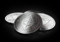 Stack of four silver Ethereum coins laying on the black background