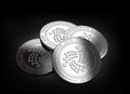 Stack of four silver IOTA coins laying on the black background