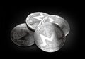 Stack of four silver Monero coins laying on the black background