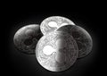 Stack of four silver Ripple coins laying on the black background