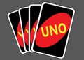 A stack of four UNO game cards showing the back face of black with red oval and the yellow UNO word dark grey backdrop