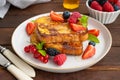 A stack of French toast on a plate with fresh berries, almond petals and honey on a dark wooden background. Delicious breakfast. Royalty Free Stock Photo