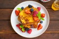 A stack of French toast on a plate with fresh berries, almond petals and honey on a dark wooden background. Delicious breakfast. Royalty Free Stock Photo