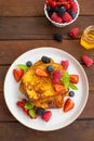 A stack of French toast on a plate with fresh berries, almond petals and honey on a dark wooden background. Delicious breakfast. Royalty Free Stock Photo