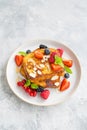 A stack of French toast on a plate with fresh berries, almond petals and honey on a gray concrete background. Delicious breakfast Royalty Free Stock Photo