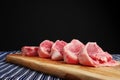 Stack of fresh raw lamb loin chops on a wooden board and white and blue table cloth, black background. Meat industry concept Royalty Free Stock Photo