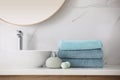 Stack of fresh towels, soap dispenser and bath bombs on countertop