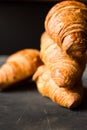 Stack of freshly baked croissants on black background, golden delicious crust,close up,eye level view