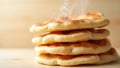 A stack of freshly baked flatbreads with steam rising on a wooden surface in a warm light setting Royalty Free Stock Photo