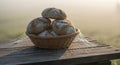Rustic Bread Rolls in Wicker Basket with Spider Web on Old Wooden Table at Sunrise Royalty Free Stock Photo