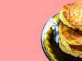 Stack of freshly fried homemade fluffy pancakes from cottage cheese on dark plate on pink wood background. Food poster