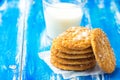 Stack of freshly home baked oatmeal and coconut cookies and glass of milk on blue wood kitchen table. Australian anzac biscuits Royalty Free Stock Photo