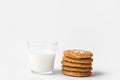 Stack of freshly home baked oatmeal and coconut cookies and glass of milk on white kitchen table. Australian anzac biscuits