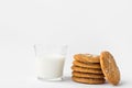 Stack of freshly home baked oatmeal and coconut cookies and glass of milk on white kitchen table. Australian anzac biscuits