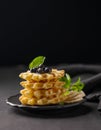 A stack of freshly prepared waffles with kiwi, banana slices and mint, drizzled with honey syrup on a gray plate against a dark Royalty Free Stock Photo