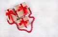 A stack of gift boxes and red coral necklace on a white wooden background. Holiday concept. Copy space Royalty Free Stock Photo