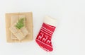 Stack of gift boxes of various sizes wrapped in craft paper tied with twine decorated with juniper red knitted Christmas stocking Royalty Free Stock Photo