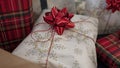 Stack of gifts wrapped in festive Christmas paper with season specific print, red shiny bows and red metallic tinsel string rope Royalty Free Stock Photo