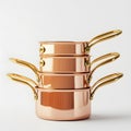 Stack of gleaming copper saucepans with polished gold handles on white background Royalty Free Stock Photo