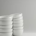 A stack of glossy white ceramic bowls is arranged asymmetrically against a light gray Royalty Free Stock Photo