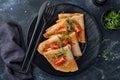 Stack of gluten free buckwheat flour crepes pancakes with cherry tomatoes and arugula microgreens on black plate on dark Royalty Free Stock Photo