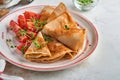 Stack of gluten free buckwheat flour crepes pancakes with cherry tomatoes and arugula microgreens on white plate, homemade healthy Royalty Free Stock Photo