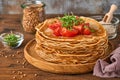 Stack of gluten free buckwheat flour crepes pancakes with cherry tomatoes and arugula microgreens on wooden plate, homemade health Royalty Free Stock Photo