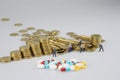 Stack of gold coin with miniature people and medicine Royalty Free Stock Photo