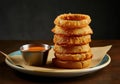 A stack of golden-brown, crispy onion rings placed on a round ceramic plate Royalty Free Stock Photo