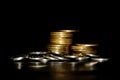 Stack of golden coins and heap of silver coins on a black background. Space for text Royalty Free Stock Photo