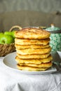 Stack of golden delicious homemade cottage cheese fritters or pancakes on white plate, rural kitchen interior